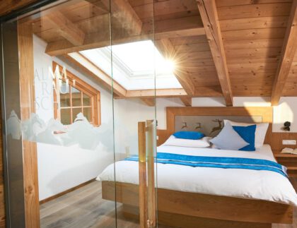 Schlafzimmer mit Holzbett und Dachfenster sowie einer Glastüre