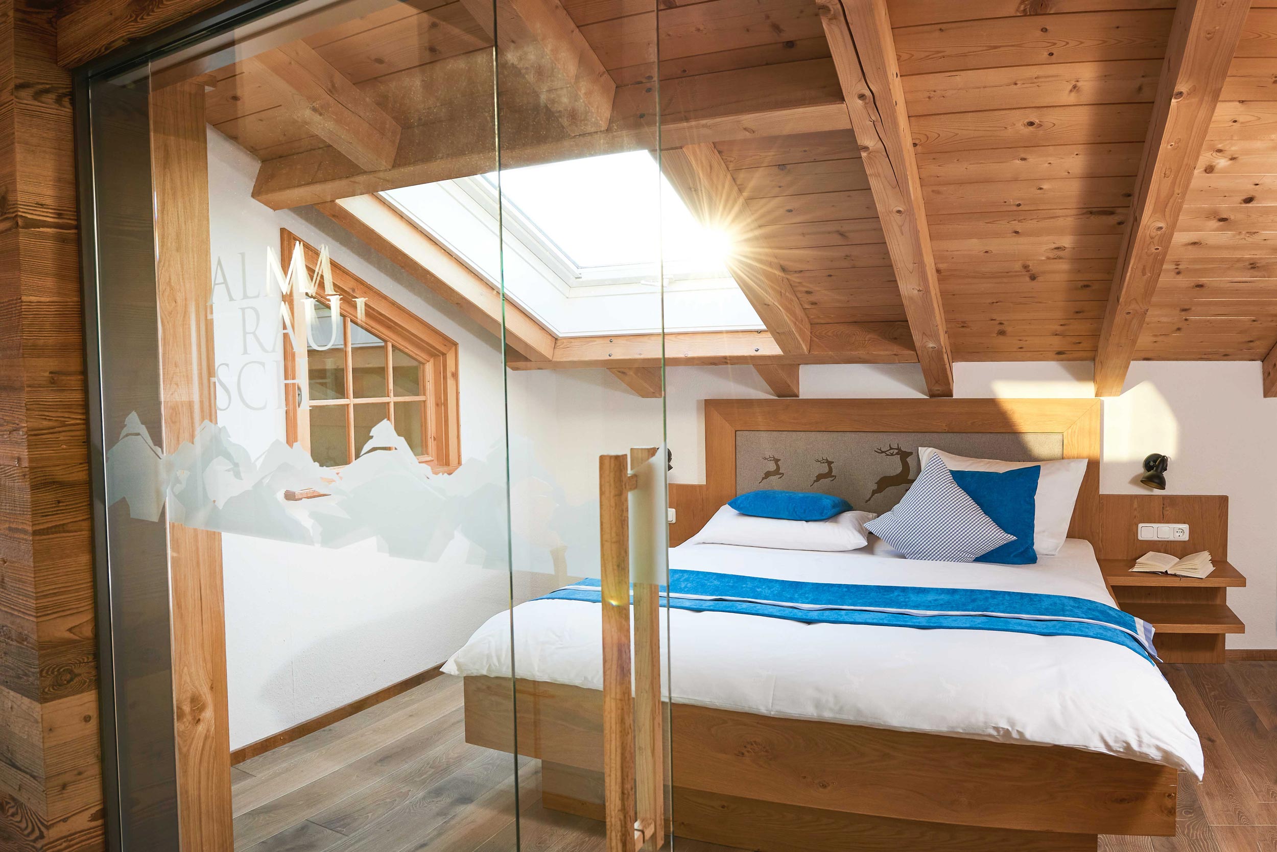 Schlafzimmer mit Holzbett und Dachfenster sowie einer Glastüre